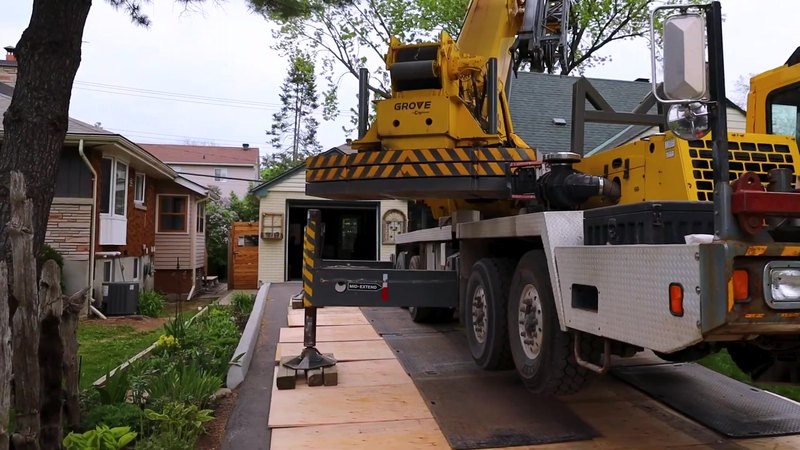 Yellow crane truck set up on a residential street for a tree removal